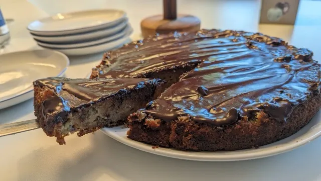 Rund banankage på et fad, hvor et enkelt stykke er skåret og trukket lidt ud, klar til servering.